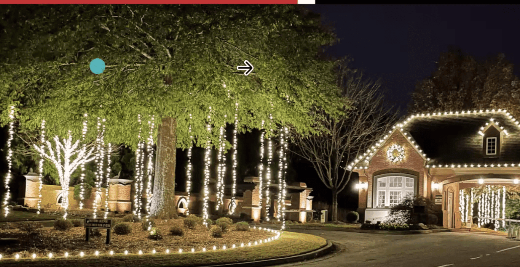 House and trees illuminated with festive white lights at night, featuring a decorated front yard and driveway.